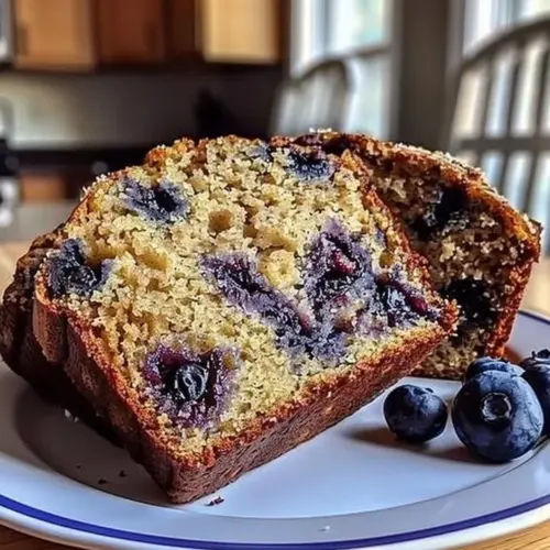 Loaf of freshly baked banana blueberry bread on a cooling rack