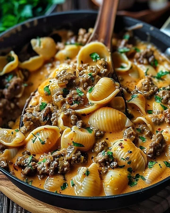 Creamy Beef Shells Bake topped with cheese and herbs in a baking dish